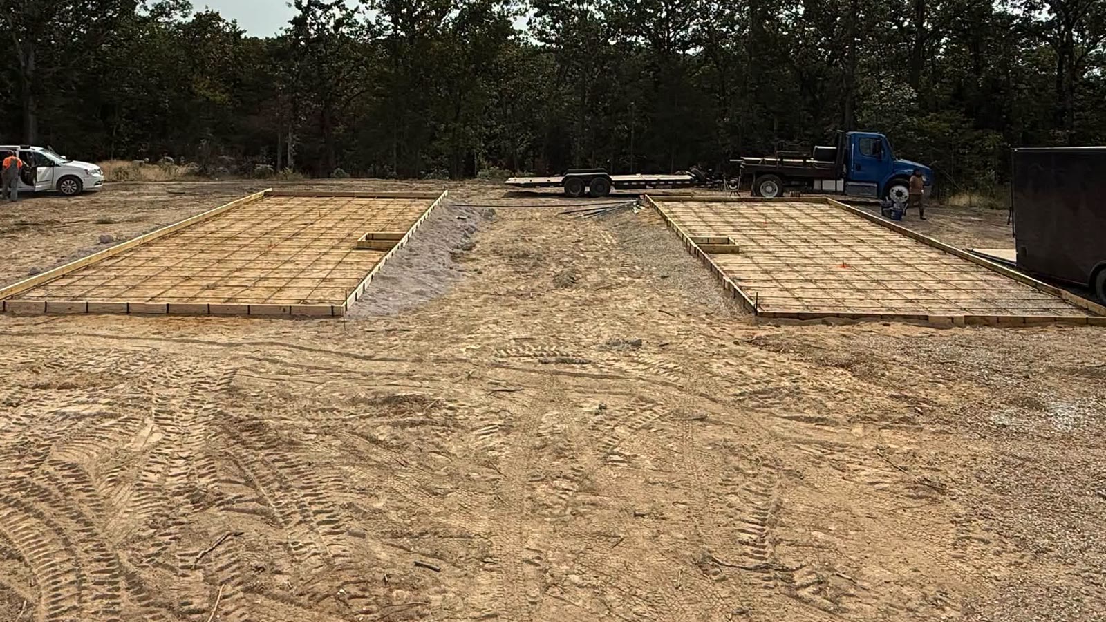 Before: wood forms and rebar set for two slabs on a cleared dirt lot
