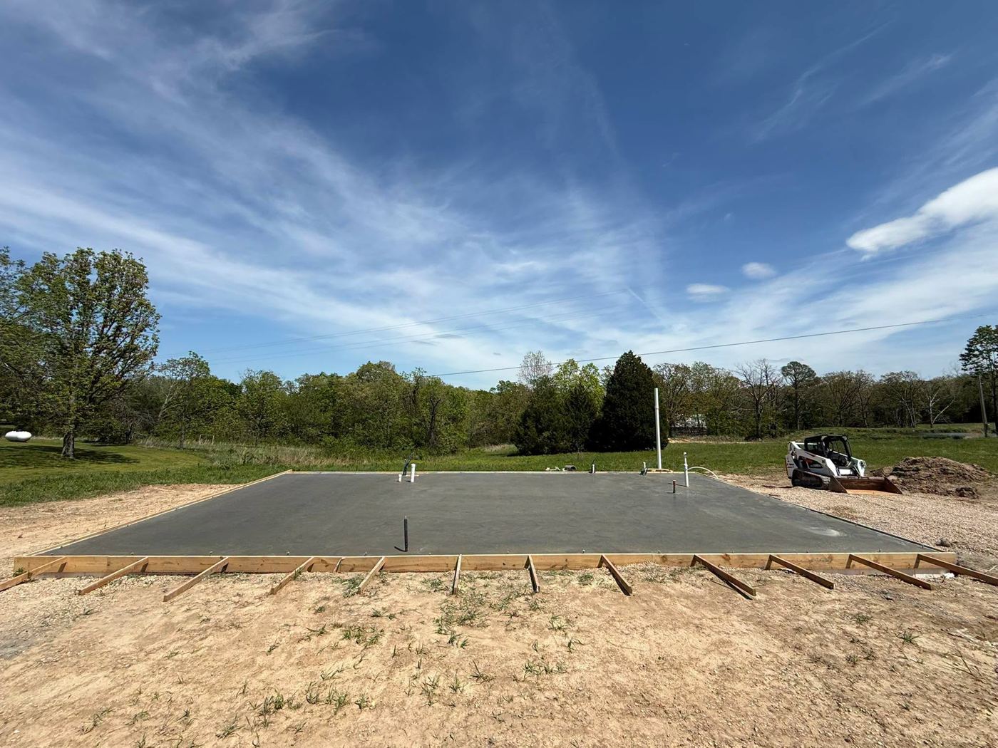 Finished concrete house slab with plumbing stubs and wood forms