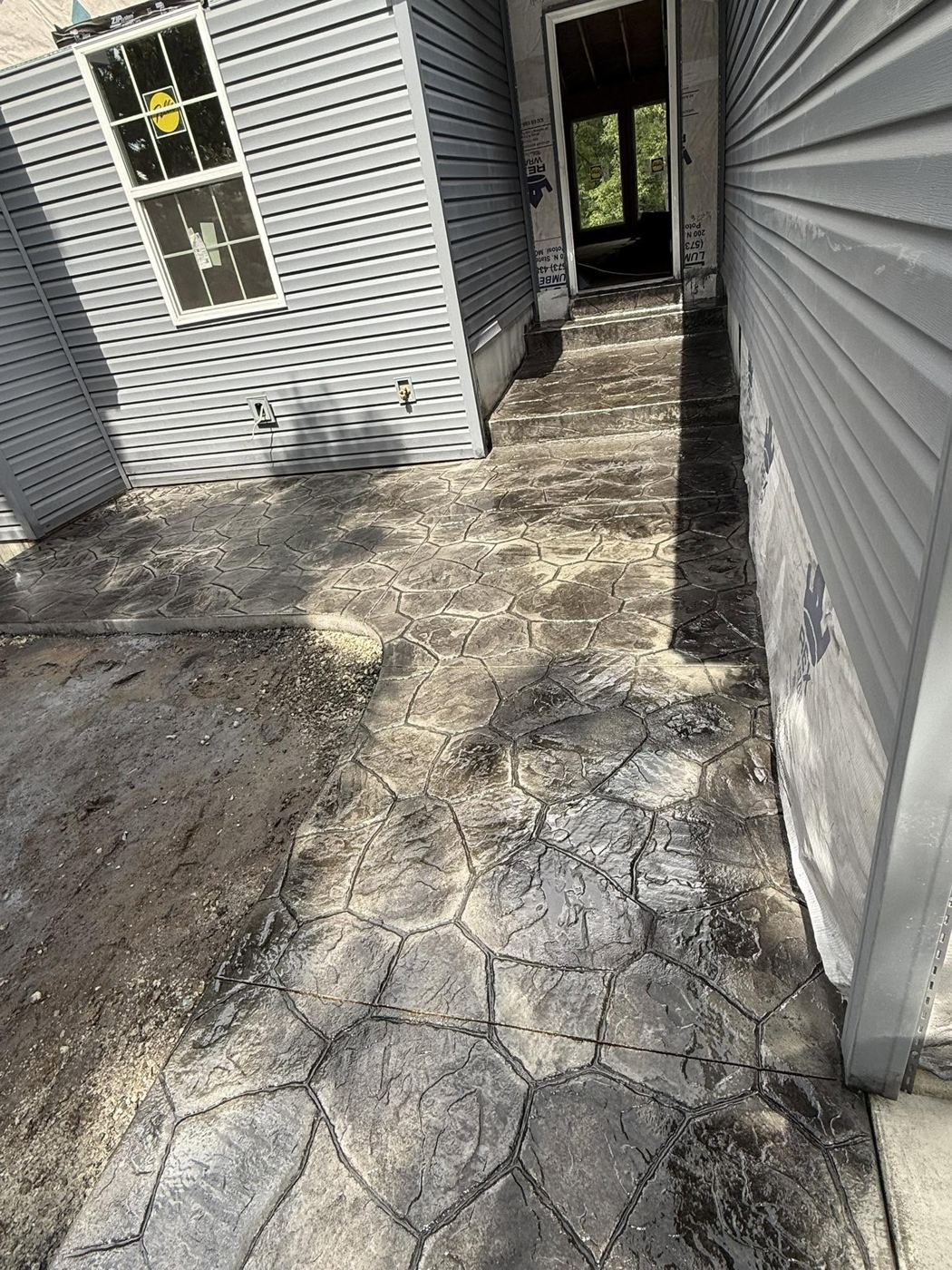 Flagstone-pattern stamped walkway and steps beside a new home
