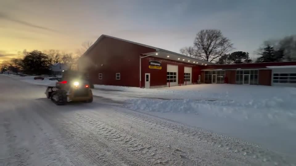 Track loader clearing snow from a business parking lot